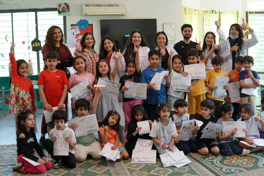 Children and Smile Center team during pediatric dental health education activity in Islamabad