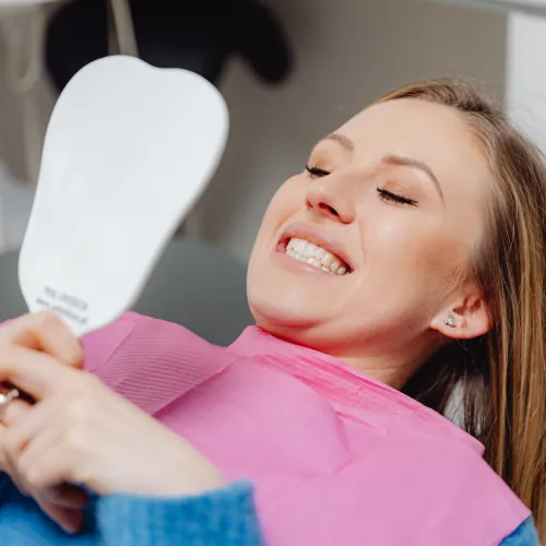 Patient smiling and checking her brighter smile after teeth whitening